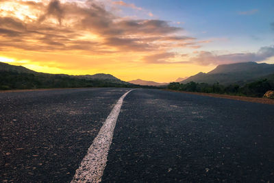 Surface level of road against sky during sunset