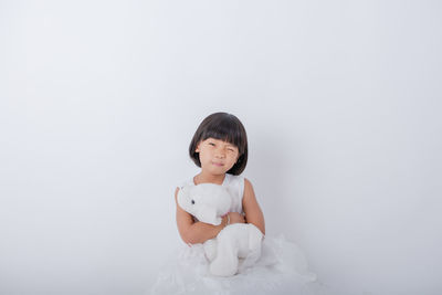 Portrait of young woman sitting against white background