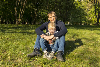 Father's day. father and son sit on grass in park, enjoying time together. summer time. happy