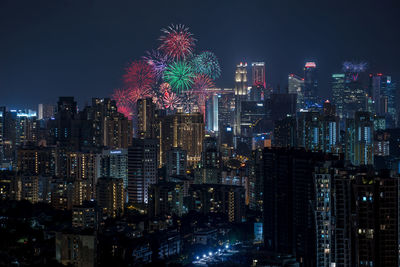 Firework display over illuminated cityscape at night