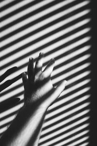 Close-up of hand touching shadow on tiled floor