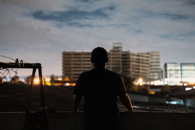 Rear view of silhouette man standing against sky during sunset