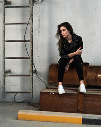 Young woman sitting against wall