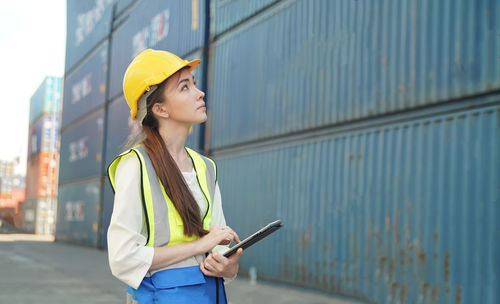 Portrait of young woman standing against wall