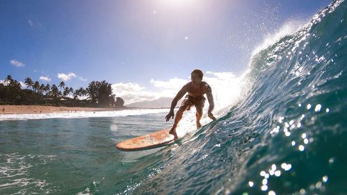 Man surfing in sea against sky