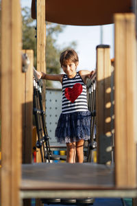 Portrait of girl standing on jungle gym in playground
