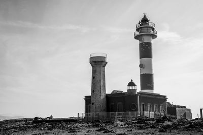 Low angle view of lighthouse by building against sky