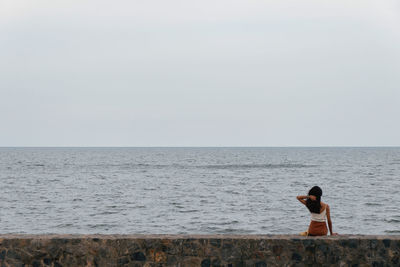 Rear view of man looking at sea against sky