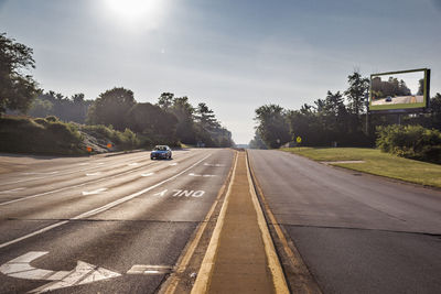 Car moving on street against sky on sunny day