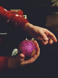 Cropped hands holding pink bauble at home