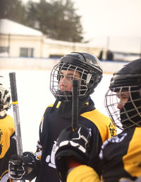 Ice hockey players holding sticks at rink