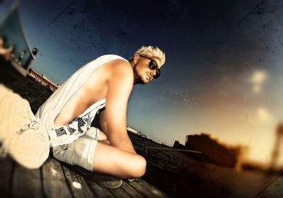 Tilt image of thoughtful man sitting at jetty against sky