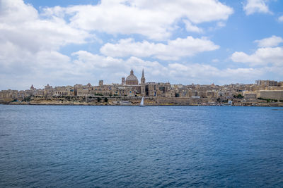 Buildings by sea against sky