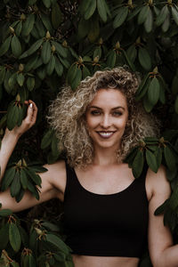 Portrait of smiling beautiful woman standing by plants at park