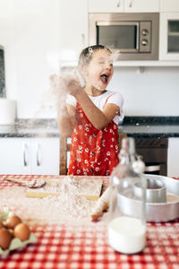 Child having fun with flour during cooking process in house