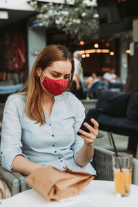 Young woman using mobile phone while sitting on table