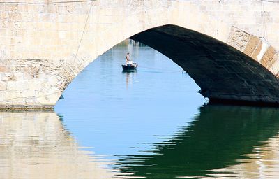 Reflection of man in boat on lake