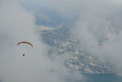 High angle view of person paragliding over mountains during foggy weather