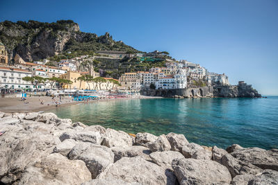 View of houses on mountain by sea against clear blue sky during sunny day