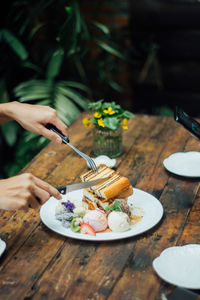 Cropped hands cutting food on table