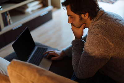 High angle view of mature man using laptop while sitting at home