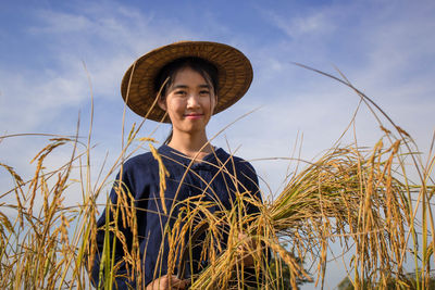 Close-up of woman wearing asian style hat on field against sky