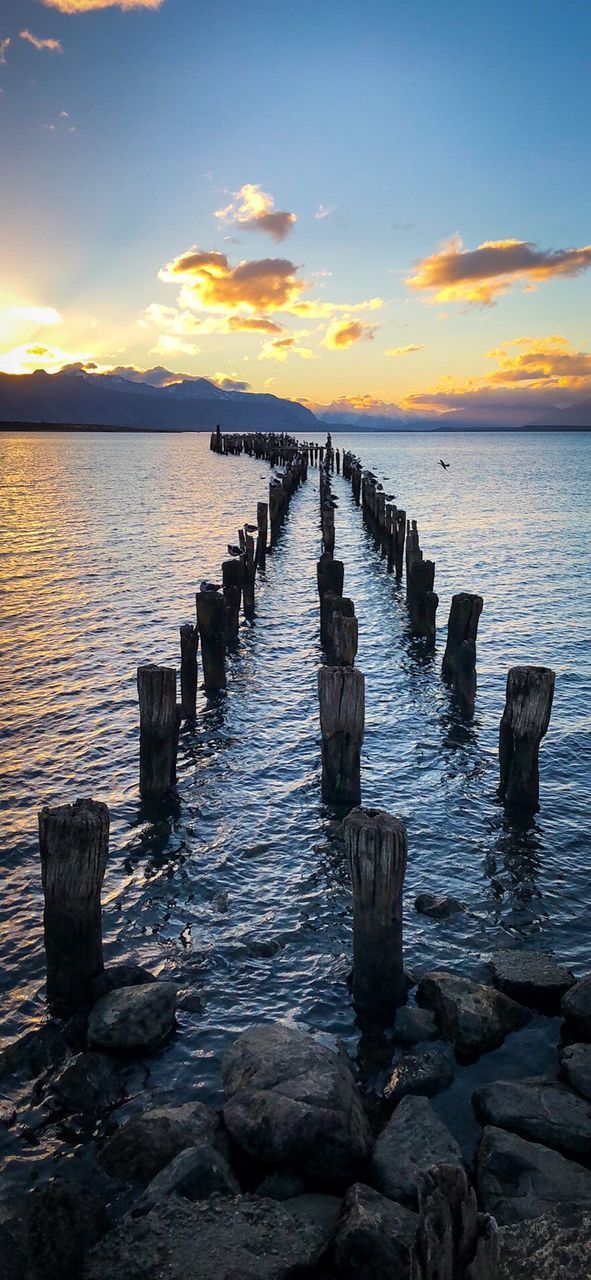 WOODEN POSTS IN SEA DURING SUNSET