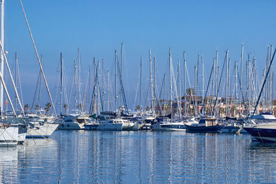 Sailboats moored on sea against clear blue sky