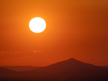 Scenic view of silhouette mountain against orange sky