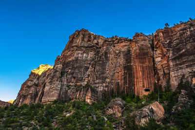 Low angle view of rock formation against clear blue sky