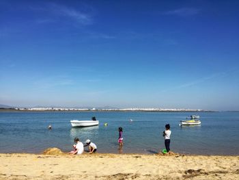 People on beach against blue sky