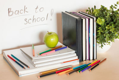 School supplies with apple and plant on table