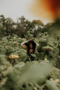 Young woman standing amidst sunflowers on field