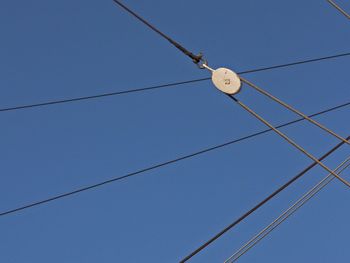 Low angle view of pulley with ropes against clear sky