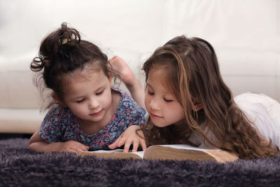 Cute sisters reading book at home