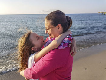 Mother and daughter at beach against sea