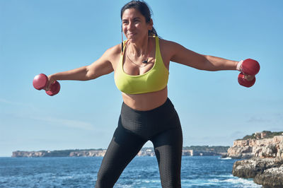 Woman exercising against sea and sky