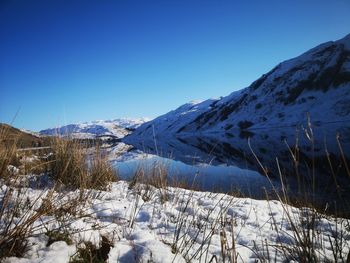 Scenic view of snowcapped mountains against clear blue sky