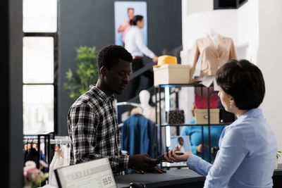 Side view of man using mobile phone while standing in office