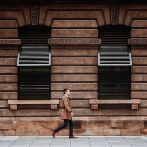 Side view of man walking in front of footpath