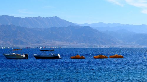 Boats in sea against mountains