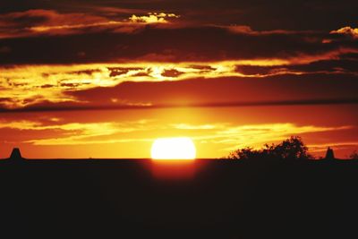 Silhouette landscape against dramatic sky during sunset