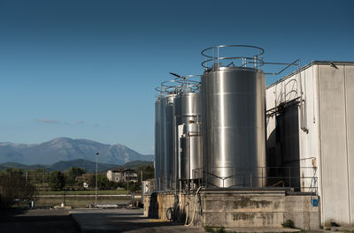 Metallic silos at industry against clear blue sky