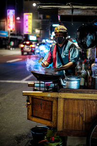 Man preparing food on street at night