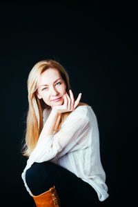 Portrait of a smiling young woman against black background