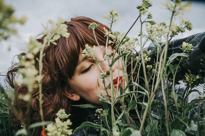 Portrait of young woman looking at flowering plants