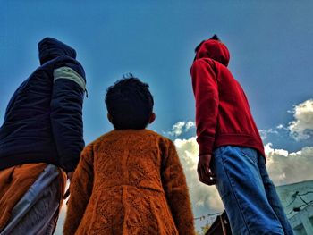 Rear view of people with umbrella against blue sky