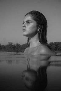 Portrait of shirtless man looking at swimming pool against sky