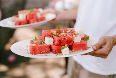 Close-up of hand holding fruit salad in plate