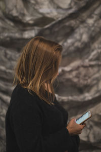 Rear view of woman using mobile phone outdoors